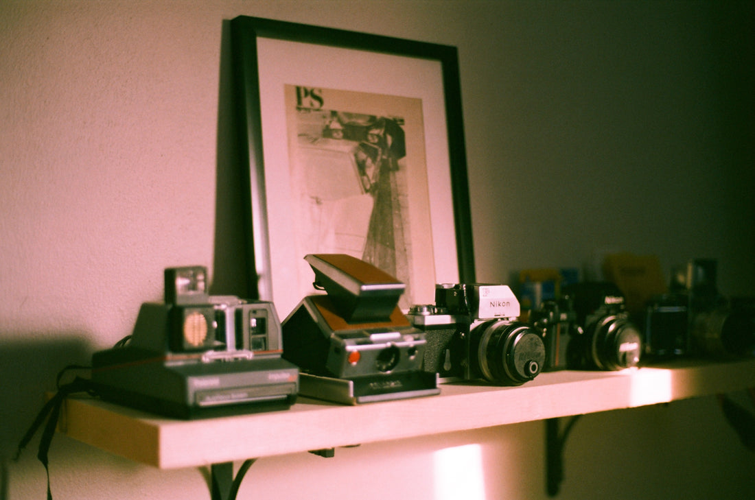 Vintage Polaroid and Nikon film cameras on a shelf
